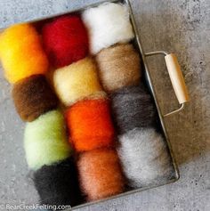 several different colors of wool in a metal container