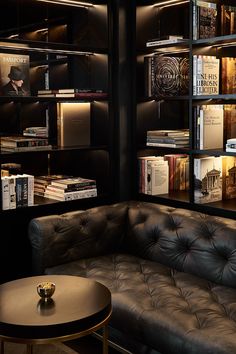 a leather couch sitting in front of a book shelf filled with books