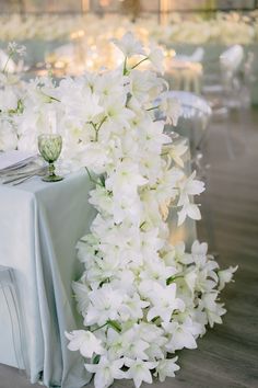 the table is set with white flowers and silverware