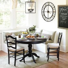 a dining room table with chairs around it and a clock on the wall behind it