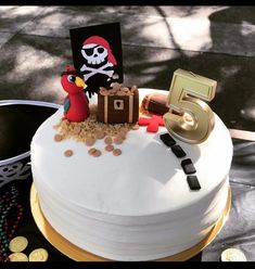 a pirate themed birthday cake on a table with coins and other items to make it look like the number five