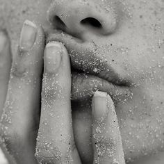 black and white photograph of a woman's face with sand on her hands, close up