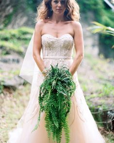 a woman in a wedding dress holding a plant