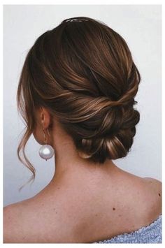 a woman with her hair in a low bun and pearl earrings on top of her head