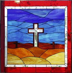 a stained glass window with a cross in the middle and blue sky behind it on a red frame