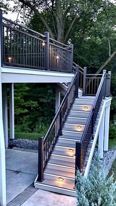 stairs leading up to the upper level of a house with lights on them and trees in the background