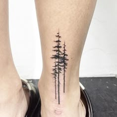 a small pine tree tattoo on the left ankle is shown in black ink, and it's surrounded by smaller trees