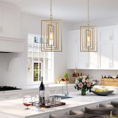 a kitchen with white counter tops and gold pendant lights hanging from the ceiling over the island