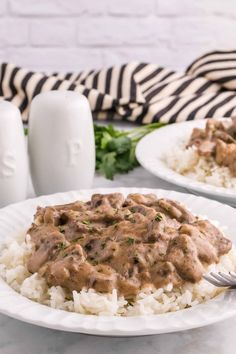 two white plates topped with rice covered in gravy