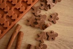 chocolate molds and cinnamon sticks on a wooden table with gingerbread cutters in the shape of cookies