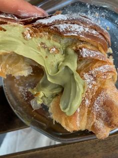 a pastry with powdered sugar and green icing on it is being held by someone