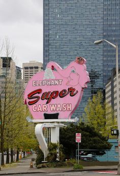 an elephant super car wash sign in front of some tall buildings with cars parked on the street