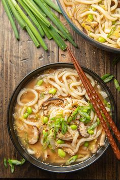 udon noodle soup in a black bowl with chopsticks on the side