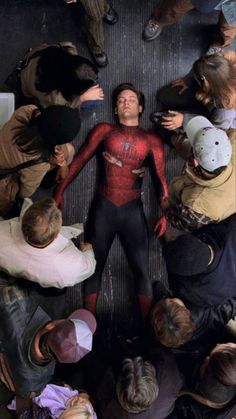 a group of people standing around each other in a circle with the spider man on their chest