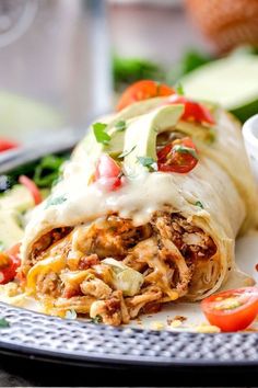 an enchilada on a plate with tomatoes and lettuce