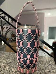 a black and pink can holder sitting on top of a counter next to a stair case