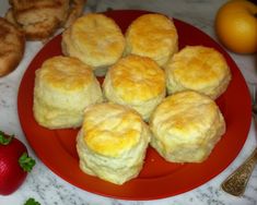 some biscuits are sitting on a red plate next to strawberries and other food items