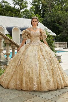 a woman in a gold gown standing by a pool