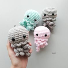 three crocheted octopus toys are being held up by someone's hand,