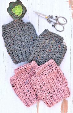 two crocheted mitts sitting on top of a wooden table next to a pair of scissors