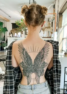 the back of a woman's body with an angel tattoo on it