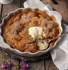 a pie with ice cream in it sitting on top of a wooden table next to purple flowers