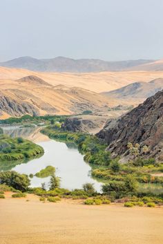 a large body of water in the middle of a desert area with mountains behind it