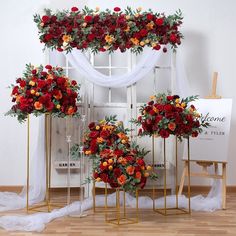 red and orange flowers are arranged on gold stands