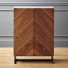 a wooden cabinet sitting on top of a hard wood floor next to a gray wall