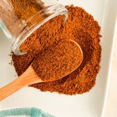 a wooden spoon filled with spices on top of a white plate