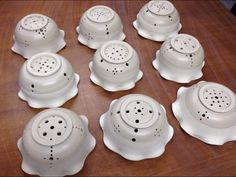 eight white dishes with black dots on them sitting on a wooden table next to each other