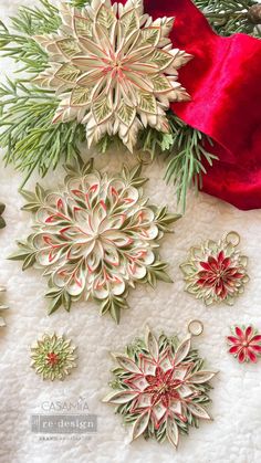 christmas ornaments are laid out on a white surface with red and green trimmings