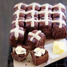 chocolate desserts with white icing are on a cooling rack next to butter cubes