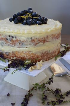 a cake sitting on top of a table covered in blueberries and lavender sprigs