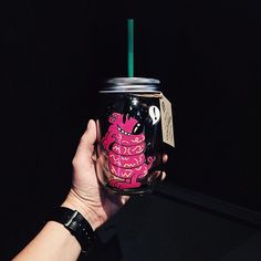 a hand holding a pink and black cup with a green straw