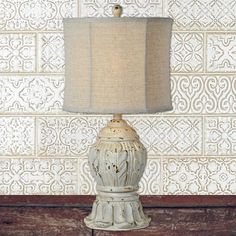 a lamp is sitting on a table next to a wall with a pattern behind it