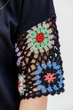 a woman's arm is covered with crochet and has colorful flowers on it