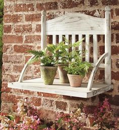 two potted plants are sitting on a wooden shelf in front of a brick wall