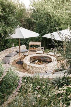 an outdoor fire pit with chairs and umbrellas