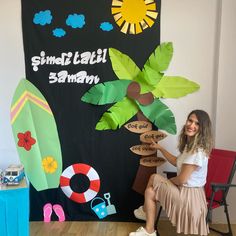 a woman sitting on a chair next to a surfboard and palm tree made out of paper