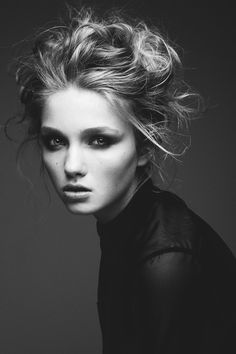 a black and white photo of a woman with her hair in a messy updo