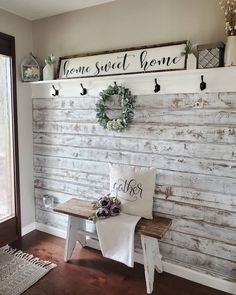 a white bench sitting in front of a wooden wall with two wreaths on it