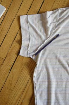 a white shirt laying on top of a wooden floor next to an open laptop computer