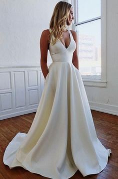 a woman in a white wedding dress standing on a wooden floor with her back to the camera