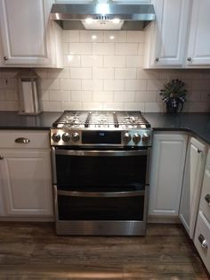 a stove top oven sitting inside of a kitchen next to white cupboards and drawers