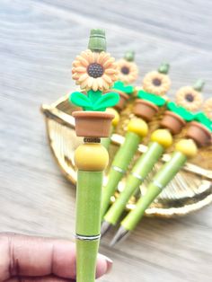 a hand holding a green bamboo stick with sunflowers on it and other decorations in the background