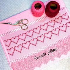 two yarns and scissors sitting on top of a piece of pink fabric with the words renata alves written across it