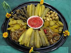 a platter filled with pickles, olives, and other vegetables on a table