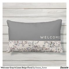 a welcome gray and white floral pillow with the word welcome on it