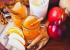 two glasses of apple cider with cinnamon and apples